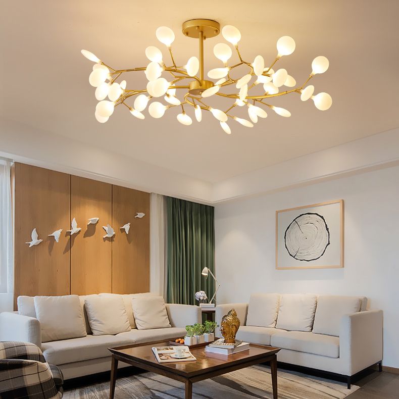 Lustre branche doré au plafond d'un salon avec canapés clairs et table basse en bois