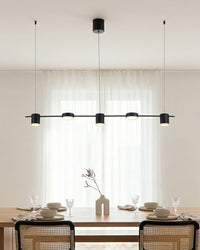 Suspension linéaire noire devant des rideaux, table dressée