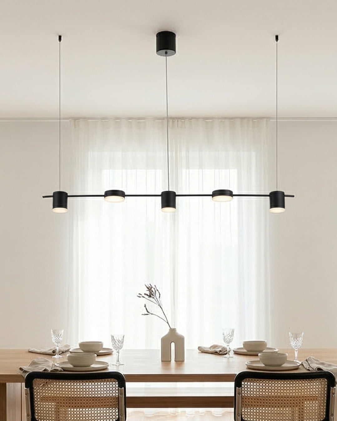 Suspension linéaire noire devant des rideaux, table dressée