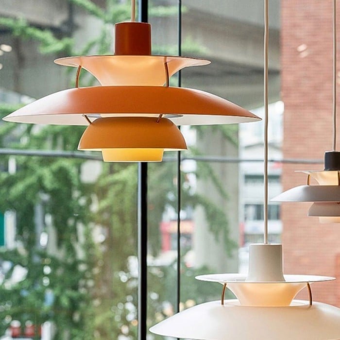 Suspension scandinave en métal coloré orange devant une grande verrière