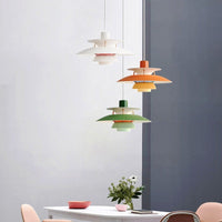 Trois suspensions scandinaves en métal coloré blanche, orange et verte au-dessus d'une table