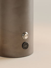 Gros plan sur le socle finition bronze et son bouton de commande