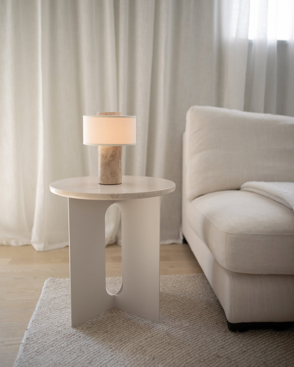 Lampe de table sans fil en travertin sur un bout de canapé blanc