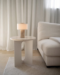 Lampe de table sans fil en travertin sur un bout de canapé blanc