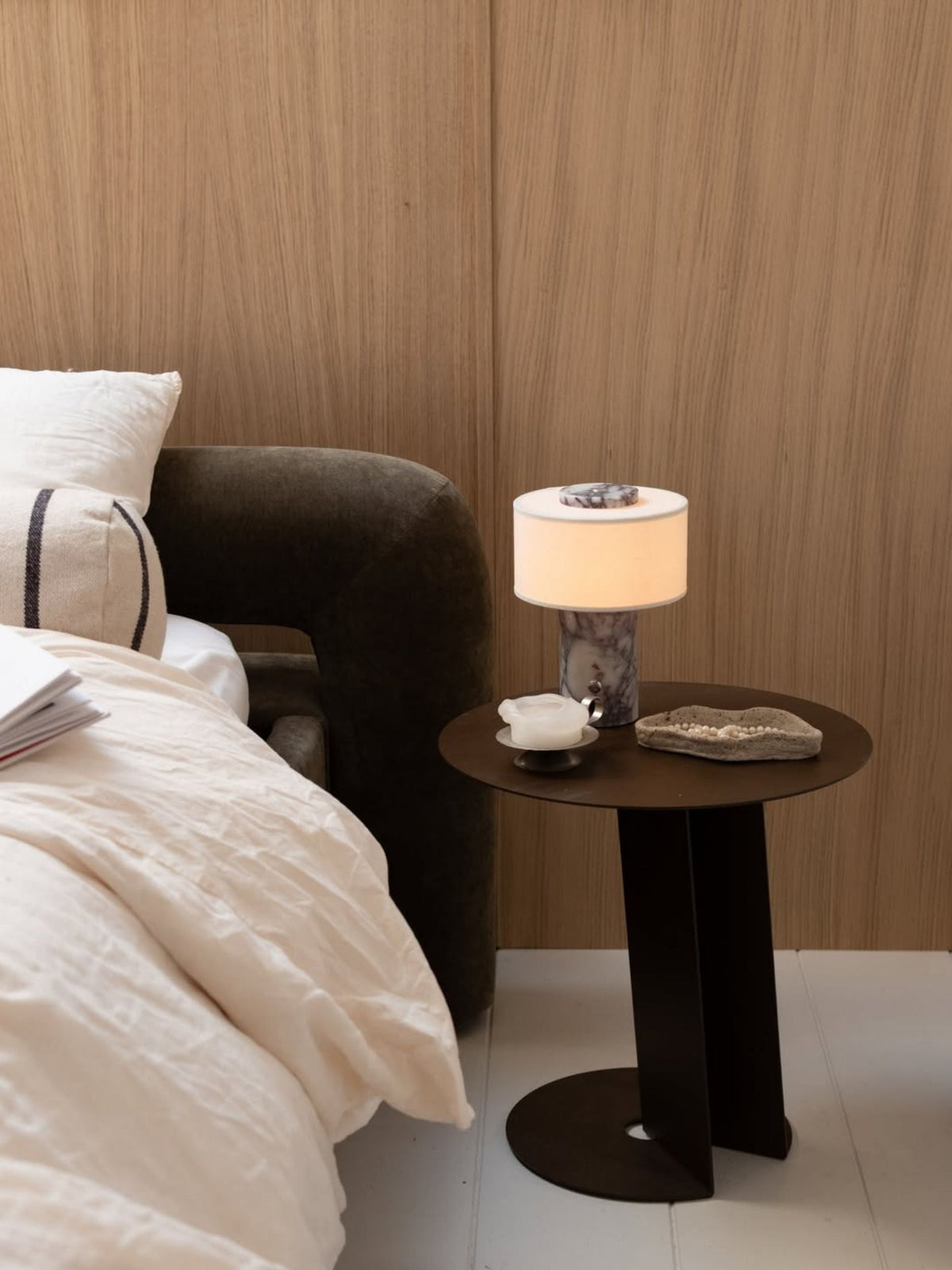 Lampe de table sans fil sur une table de chevet ronde à côté d'un lit