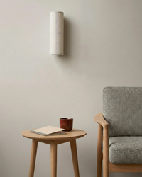 Applique murale design japandi éteinte dans un salon avec fauteuil en bois clair