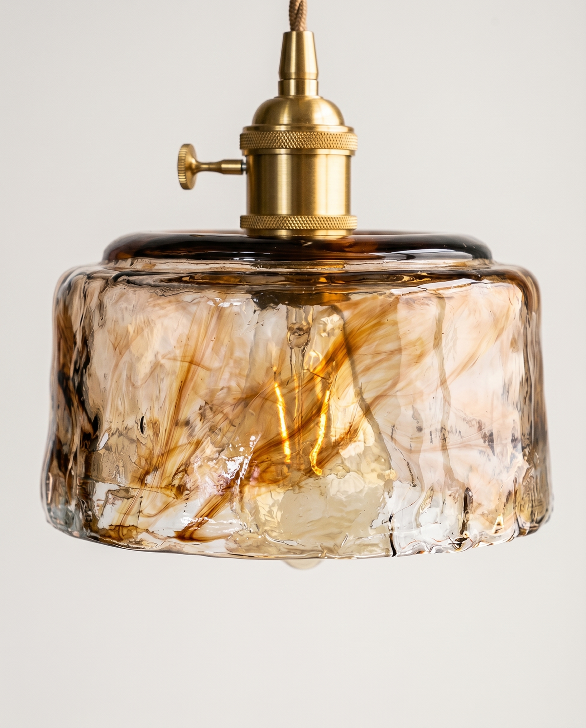 Suspension verre ambré vintage éclairée, reflets chauds sur le verre texturé