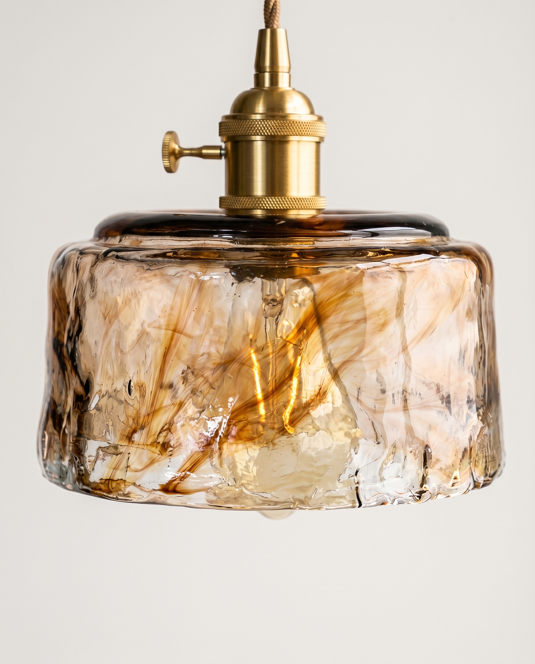 Suspension verre ambré vintage éclairée, reflets chauds sur le verre texturé