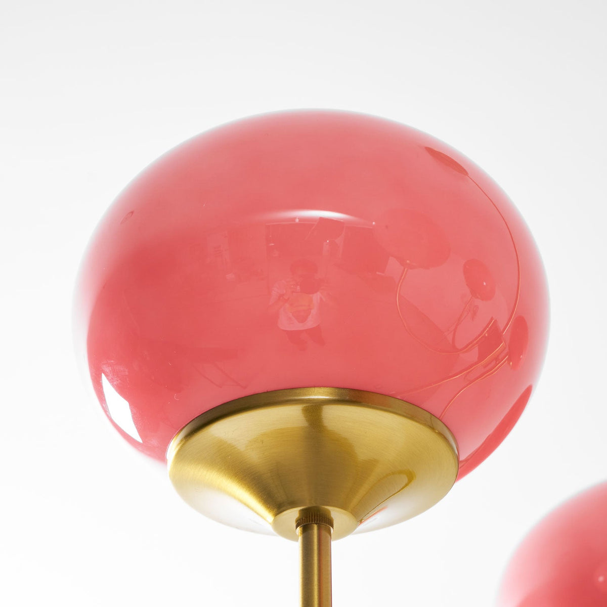 Gros plan sur un abat-jour en verre rose laqué et sa bague métallique