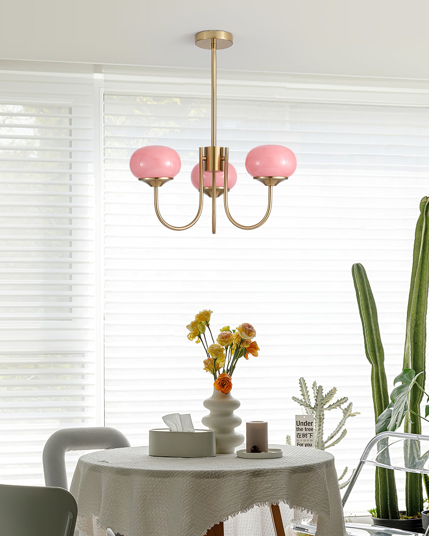 Lustre en verre rose au-dessus d'une table ronde avec vase fleuri