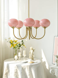 Lustre en verre rose cinq lumières au-dessus d'une table dressée