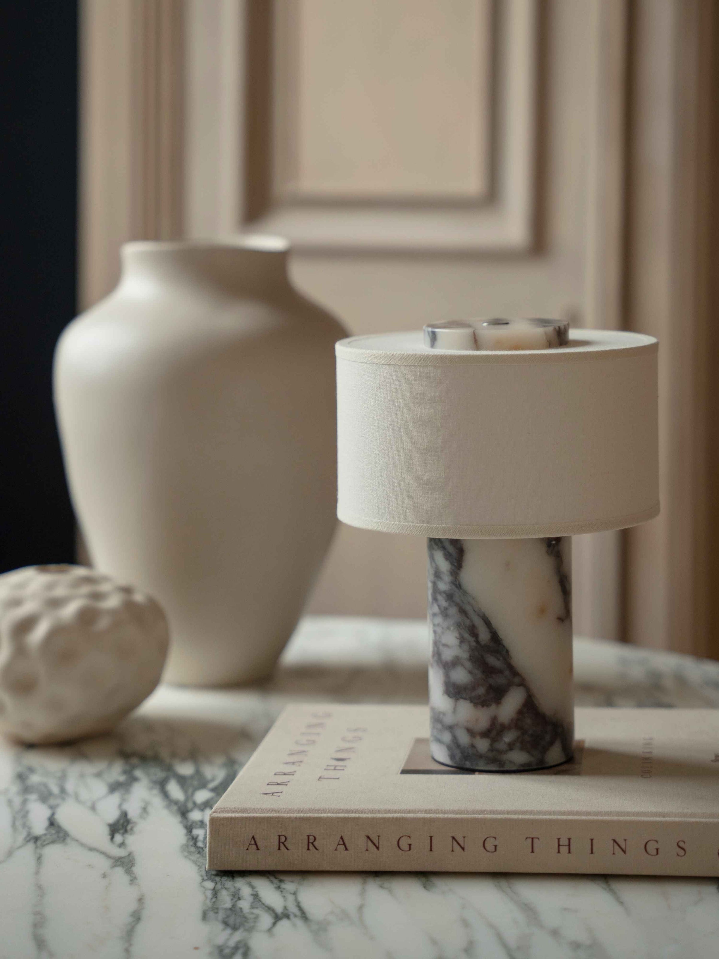 Lampe de table sans fil posée sur un livre et un plateau en marbre