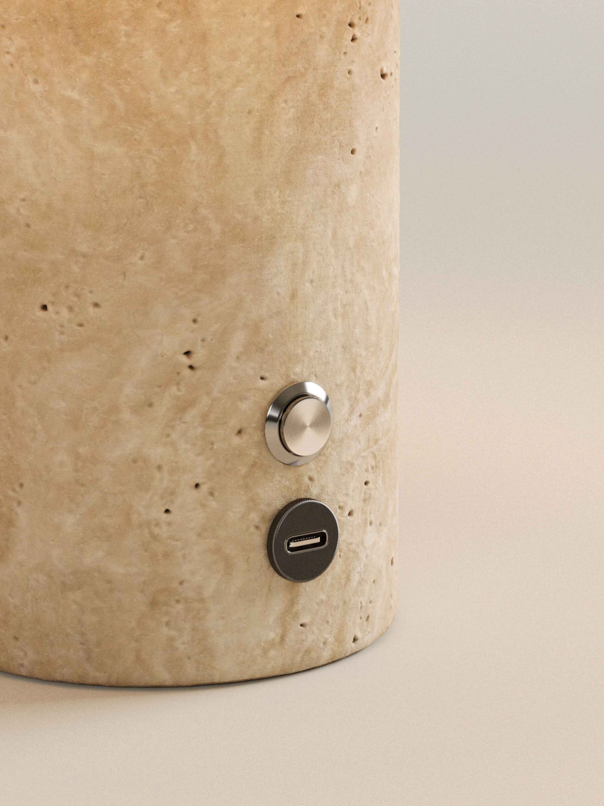 Gros plan sur le socle en travertin, son bouton et son port USB-C