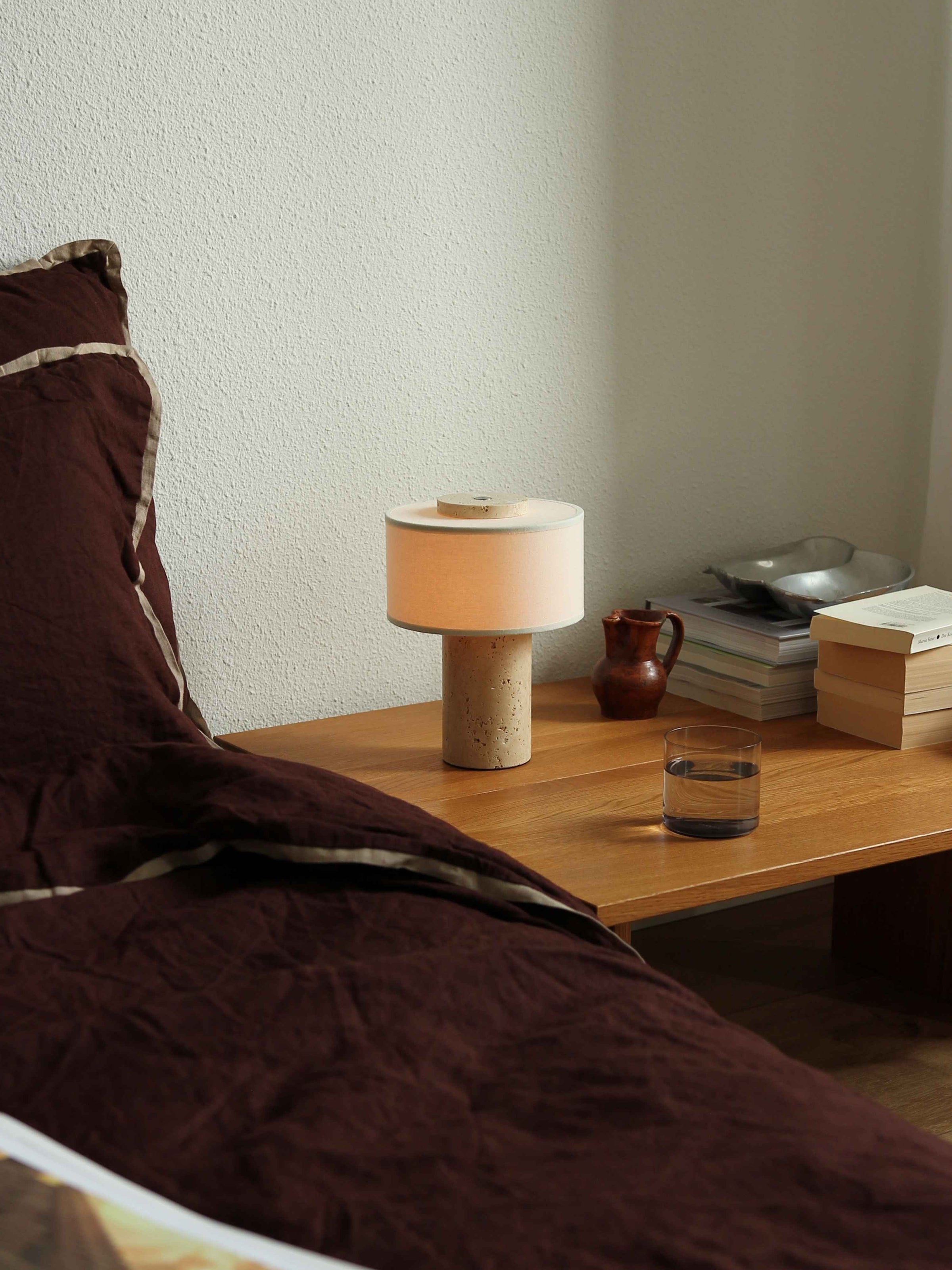 Lampe de table sans fil en travertin allumée dans une chambre