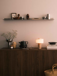 Lampe de table sans fil en travertin sur un buffet devant un mur rose