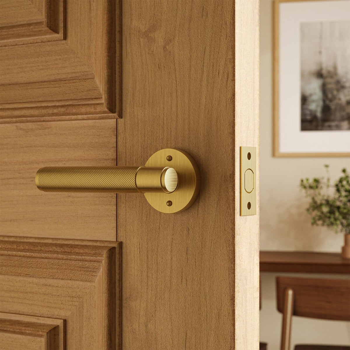 Poignée de porte laiton brossé sur porte en bois clair