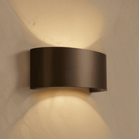 Applique murale LED étanche noire incurvée éclairant un mur en plâtre