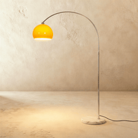 Lampadaire design avec abat-jour orange allumé et base en marbre blanc