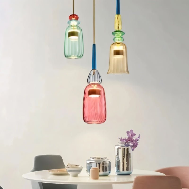 Trio de suspensions verre vitrail vert, ambre et rouge au-dessus d'une table blanche
