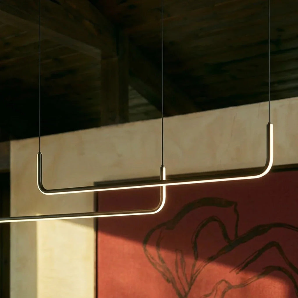 Détail du lustre design linéaire éclairé devant un mur coloré