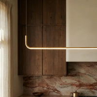 Lustre design linéaire diffusant une lumière chaude dans une cuisine en bois