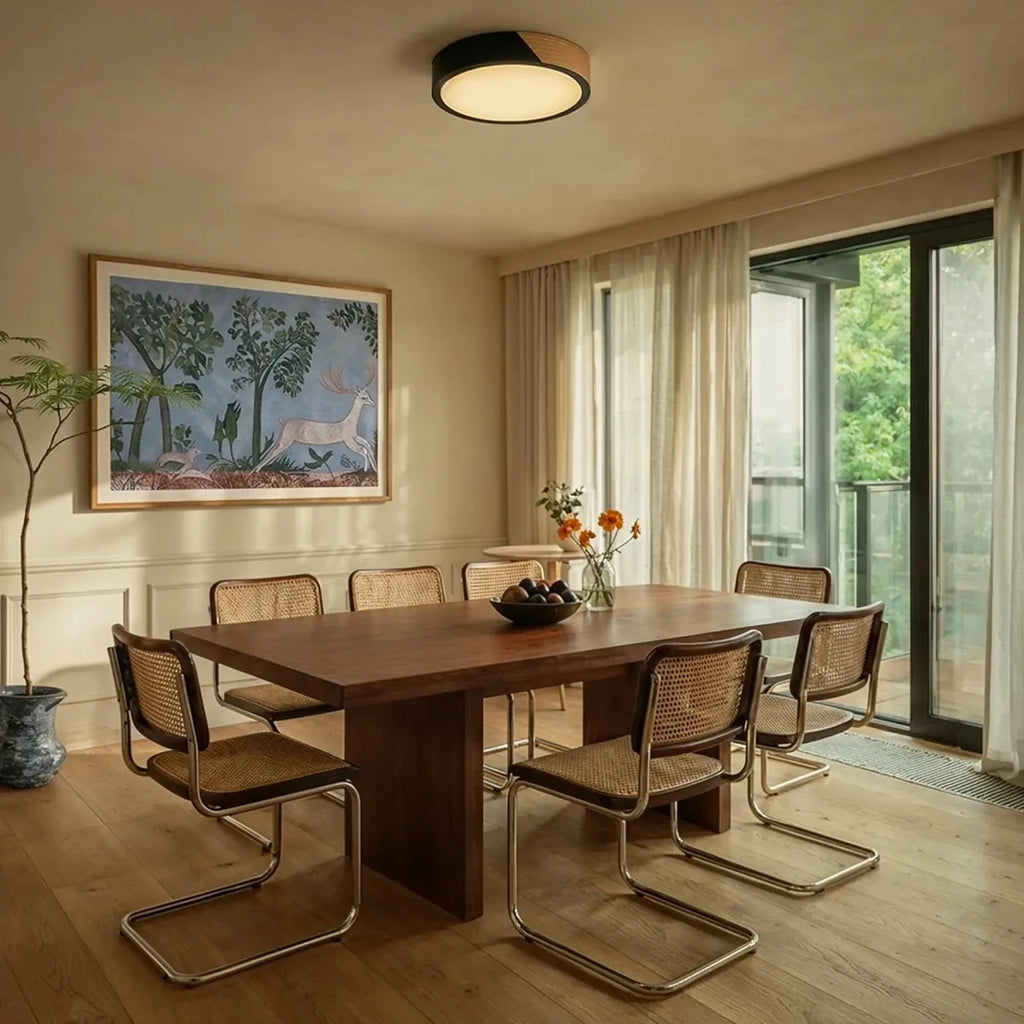 Plafonnier LED rond noir et bois dans une salle à manger baignée de lumière