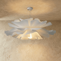 Lustre design fleur blanc allumé aux pétales ondulés sous un plafond beige