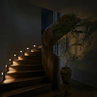 Escalier hélicoïdal en bois éclairé la nuit par des spots muraux encastrés