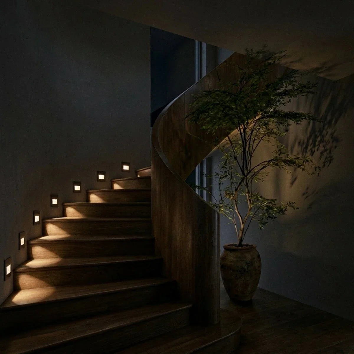 Escalier hélicoïdal en bois éclairé la nuit par des spots muraux encastrés