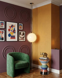 Lampadaire boule en chrome dans un salon aux murs prune