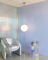 Lampadaire boule en chrome devant un mur iridescent
