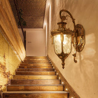 Applique murale extérieure lanterne bronze éclairant un escalier en bois