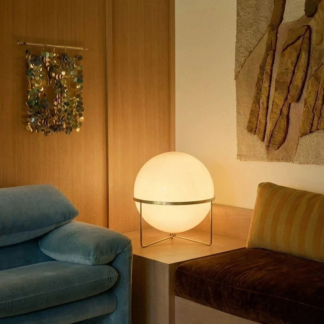 Lampadaire design à sphère posé près d'un canapé bleu