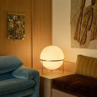 Lampadaire design à sphère posé près d'un canapé bleu