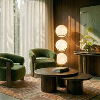Lampadaire design à trois sphères dans un salon aux fauteuils verts