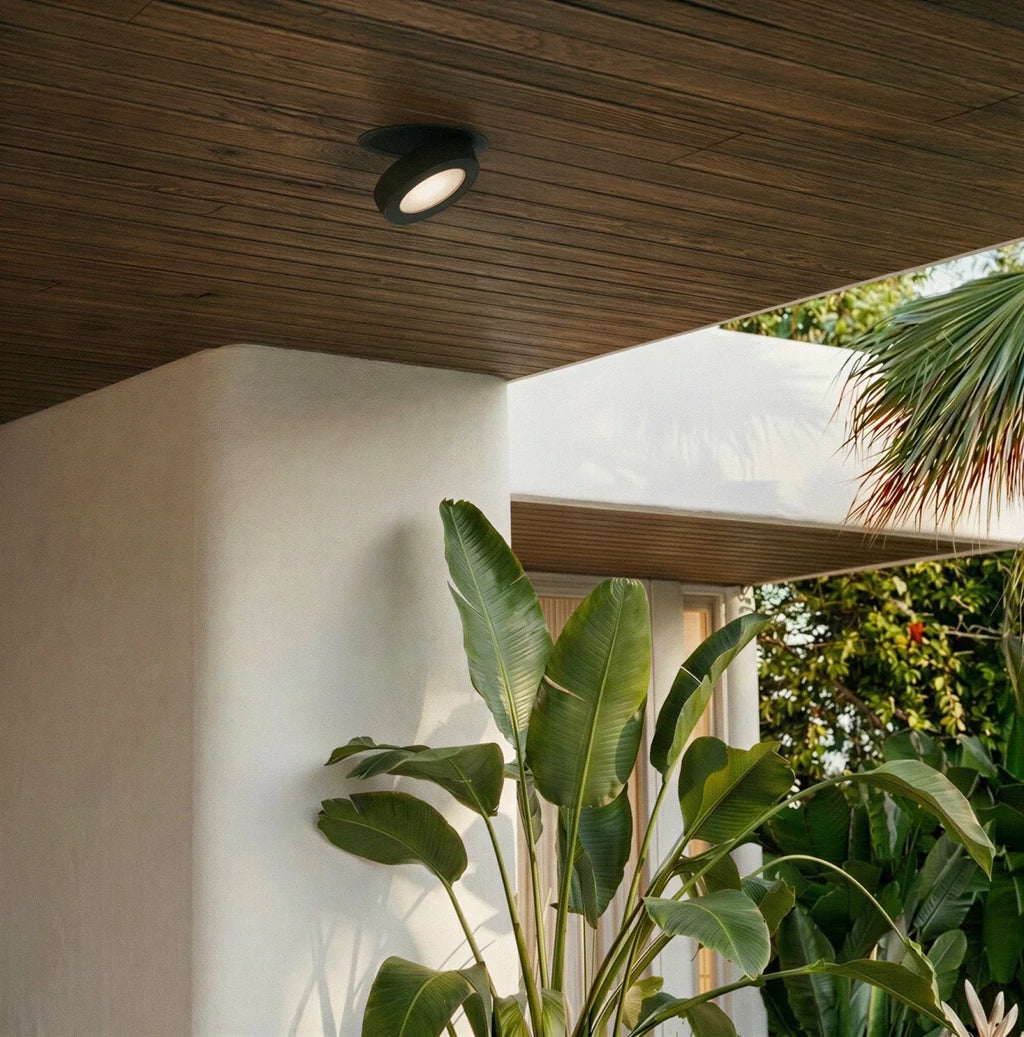 Spot encastrable orientable noir sous un auvent en bois donnant sur un jardin