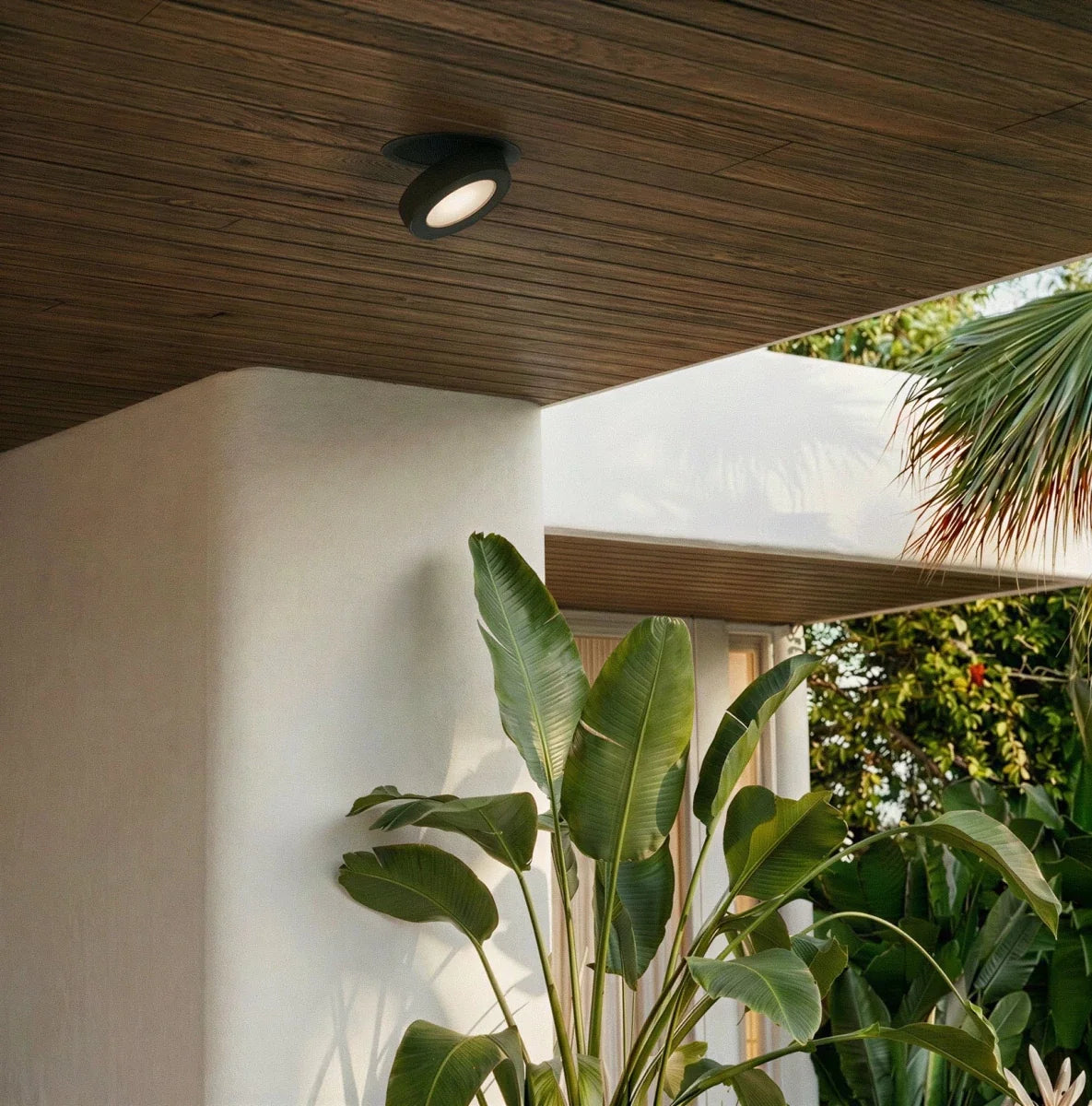Spot encastrable orientable noir sous un auvent en bois donnant sur un jardin