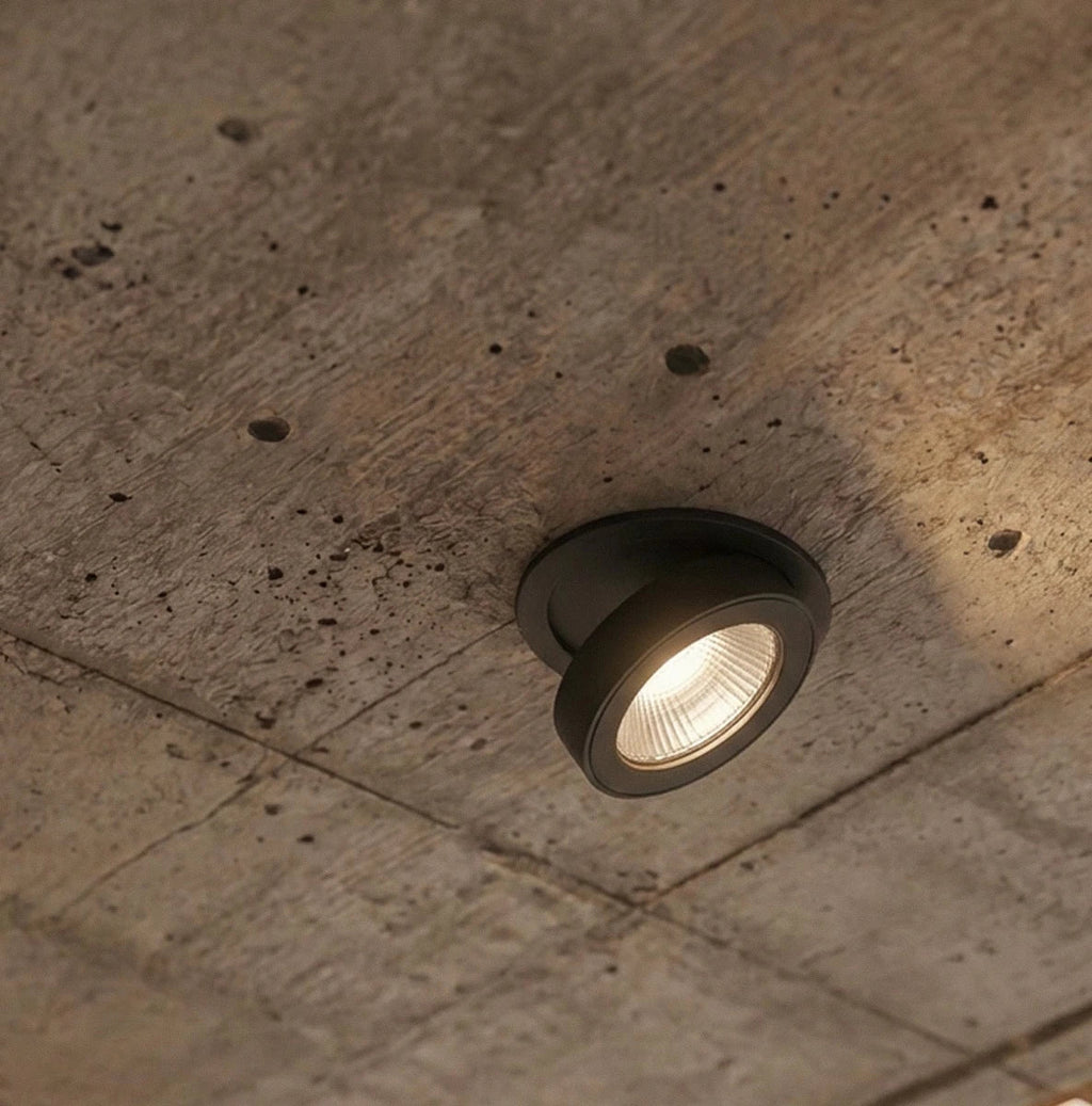 Gros plan sur la tête orientable du spot en aluminium noir sur béton brut