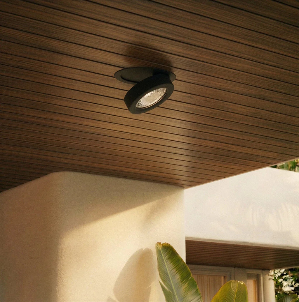 Spot encastrable orientable noir sous un plafond en lattes de bois