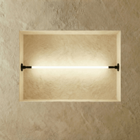 Applique murale LED linéaire noire allumée sur un mur neutre, vue de face