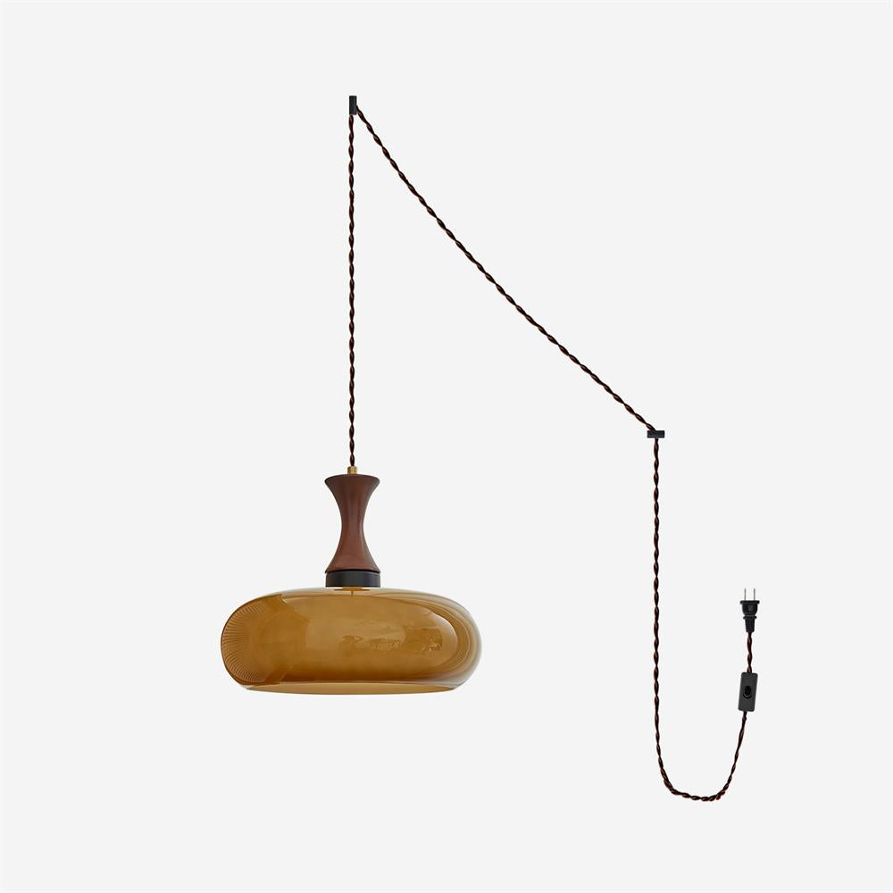 Suspension baladeuse en verre ambre avec son cordon et sa prise sur fond blanc