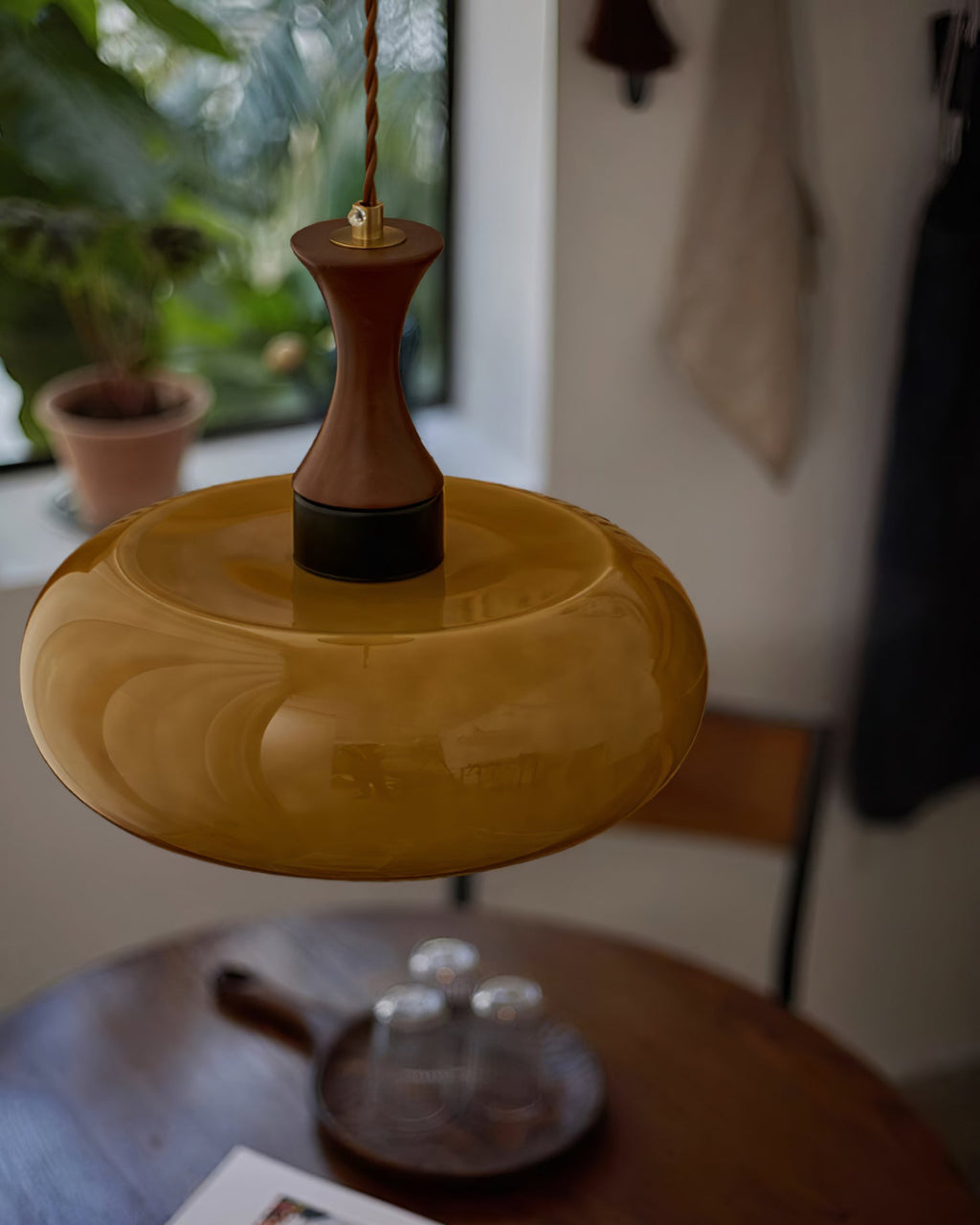 Suspension baladeuse en verre ambre au-dessus d'une table ronde en bois foncé