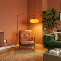 Suspension baladeuse en verre dans un salon bohème avec tapis et plantes