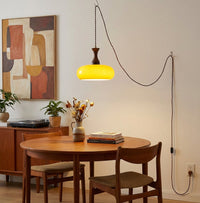 Suspension baladeuse en verre au-dessus d'une table ronde en bois clair