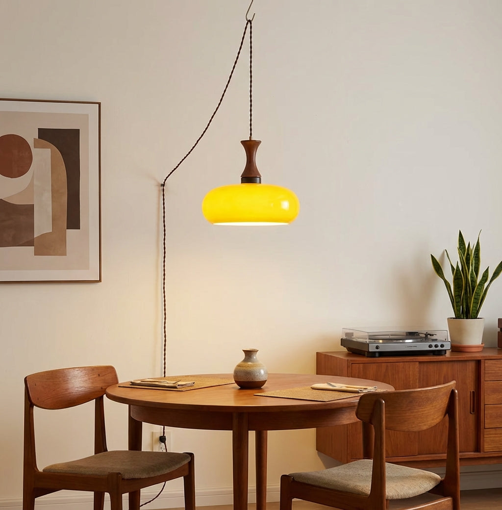 Suspension baladeuse en verre éclairant une table à manger et son enfilade