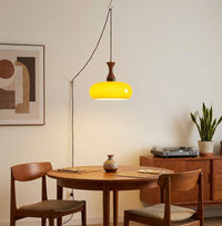Suspension baladeuse en verre éclairant une table à manger et son enfilade