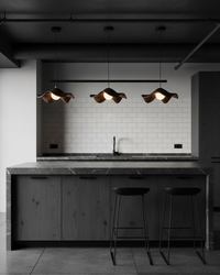 Trois suspensions design organique alignées au-dessus d'un îlot de cuisine sombre