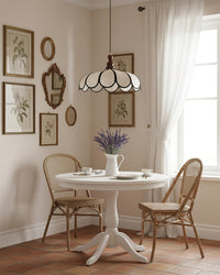 Suspension en fibre naturelle au-dessus d'une petite table ronde et de chaises en bois