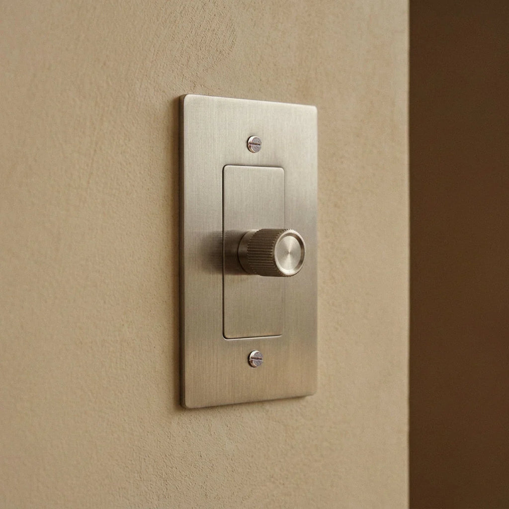 Gros plan sur un variateur de lumière en acier inoxydable sur un mur clair