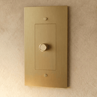 Variateur de lumière en laiton doré 1 poste sur un mur beige